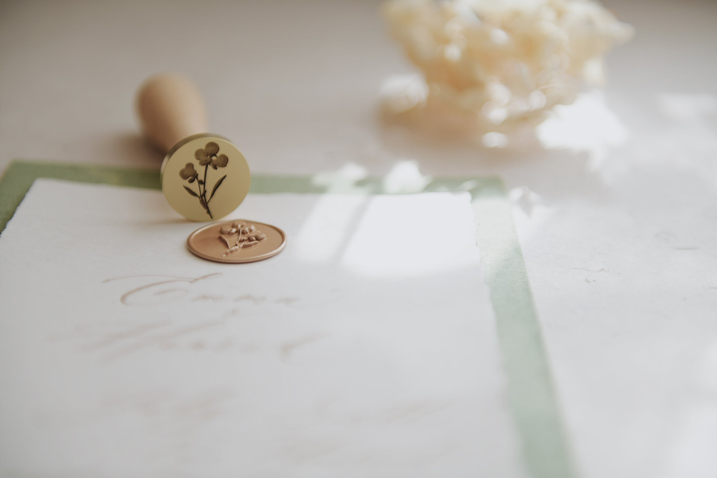 pelargondesign-gold_pelargon flower wax-seal-on_a_stack_of_green white cotton_paper_mood_picture